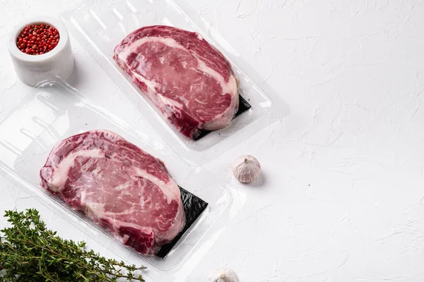 Fresh raw red meat vacuum sealed in plastic set, on white stone table background, with copy space for text