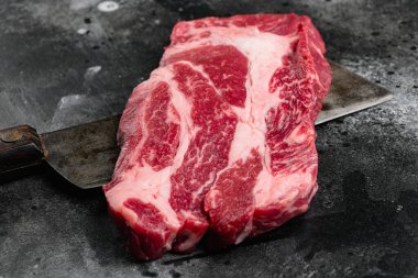 Chuck rulo biftek seti, siyah taş masa arkaplanı üzerinde, metin için kopyalama alanı ile