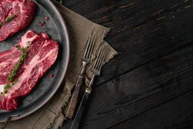 Taze Chuck rulo biftek seti, siyah ahşap masa arkaplanı, üst görünüm düz, metin için kopyalama alanı ile
