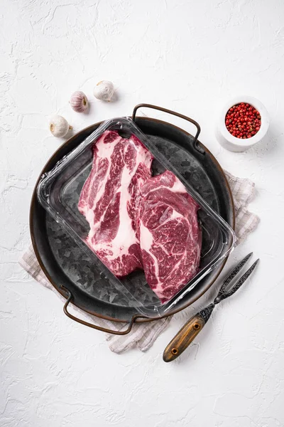 Chuck roll beef steak, vacuum packed set, on white stone table background, top view flat lay