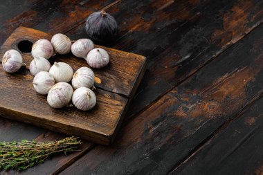 Küçük, taze sarımsak seti, eski, siyah ahşap masa arkasında.