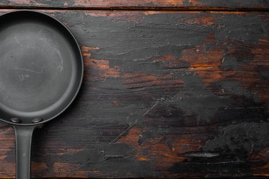 Metin ya da yemek için metin ya da yiyecek için kopyalama alanı olan büyük tava seti, üst görünüm düz, eski koyu ahşap masa arkaplanı