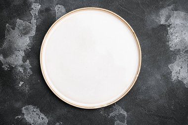 Metin veya yiyecek için kopyalama alanı olan beyaz rustik seramik plaka seti, üst görünüm düz, siyah koyu taş masa arkaplanı üzerinde
