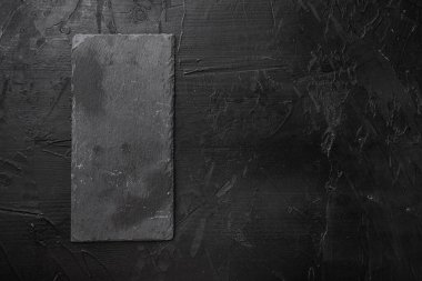Metin veya yiyecek için kopyalama alanı olan siyah taş kesme tahtası seti, üst görünüm düz, siyah taş masa arkaplanı üzerinde