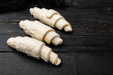 Çiğ taze kruvasan seti, siyah ahşap masa zemininde, metin için kopya alanı ile