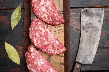 Çiğ et, pirzola seti, eski koyu ahşap masa arkaplanı, üst manzara düz yatıyordu