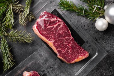 Noel ve Yeni Yıl setine sığır eti misketli biftek paketi, siyah siyah taş masa arkaplanı, üst görünüm düz yatıyordu
