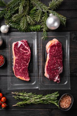 Noel ağacı süslemeli çiğ biftek, siyah ahşap masa arkaplanı, üst manzara düz.