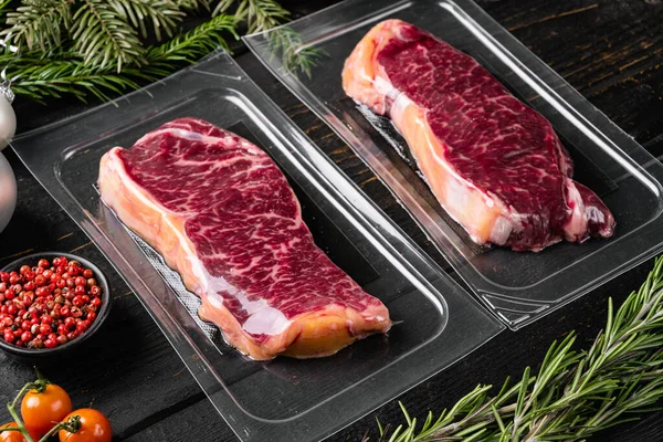Fresh raw red meat vacuum sealed in plastic set, on black wooden table background