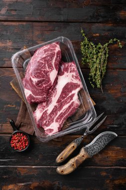 Süpürge paketlenmiş et, Chuck rulo biftek seti, eski siyah ahşap masa arkaplanı, üst manzara düz yatıyordu