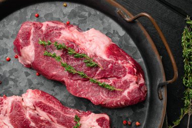 Chuck 'ın gözleri yuvarlanmış biftek seti, siyah ahşap masa arkaplanı, üst manzara düz yatıyordu