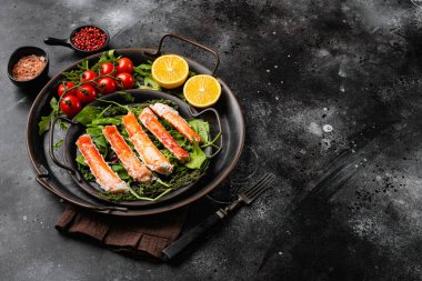Taze limon dilimleri ve tereyağı soslu kar yengeci bacakları, siyah taş masa zemininde, metin için kopya alanı ile birlikte.