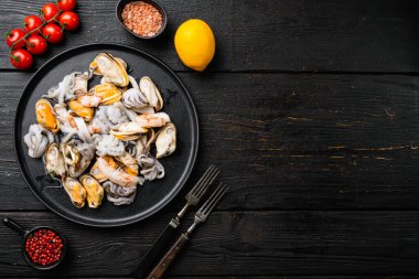 Karides, mürekkep balığı midyesi ve ahtapot seti ile deniz ürünleri tahtası, siyah ahşap masa arkaplanı, üst görünüm düz, metin için kopyalama alanı ile