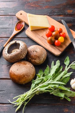 Portabello mantarları fırın, çedar peyniri, kiraz domatesleri ve adaçayı eski karanlık masa, kenar görüş için.