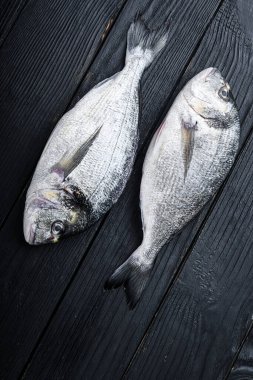 Çiğ dorado ya da çipura balığı, siyah ahşap masa manzaralı.