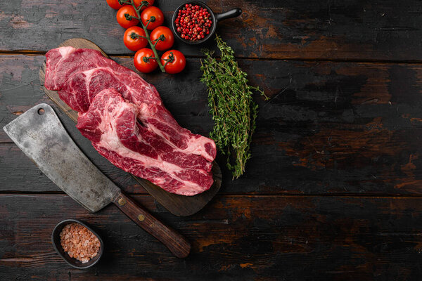 Raw fresh Chuck roll steak with herbs set, on old dark  wooden table background, top view flat lay, with copy space for text