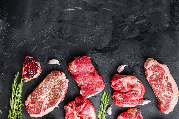 Set of various alternative raw meat steaks  over black background top view. With space for text