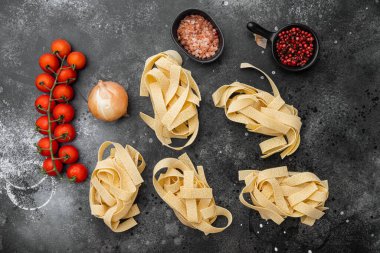 Çiğ makarna malzemesi seti, siyah taştan masa arkaplanı, üst görünüm düz yatıyordu