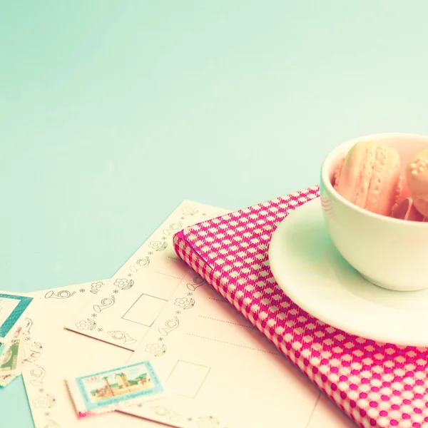 Macaroons in cup on retro book — Stock Photo, Image