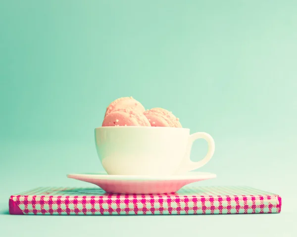 Macaroons in cup on retro notebook — Stock Photo, Image