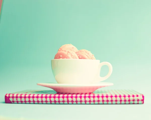 Macaroons in cup on retro notebook — Stock Photo, Image