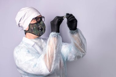 Solunum cihazı ve eldiven takan bir doktor dijital termometreye bakıyor..