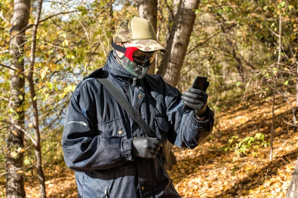 在Covid 19期间 一名戴着呼吸器面具 拨打智能手机的男子在森林中行走 — 图库照片