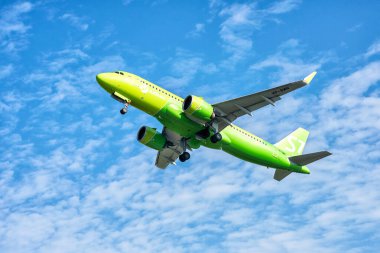 Mavi gökyüzünün arka planında uçan büyük sarı bir jet.