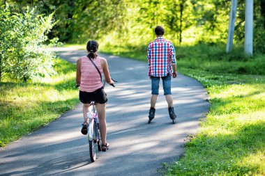 Yazın bisiklet süren ve parkta paten kayan iki arkadaş.. 