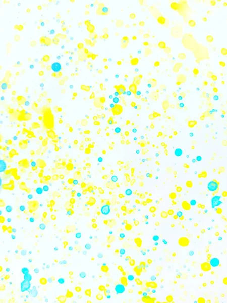 Spetterende gele en blauwe verf op witte papieren ondergrond. — Stockfoto
