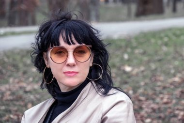 Parkta oturan siyah saçlı, orta yaşlı, güzel bir Avrupalı kadının portresi.