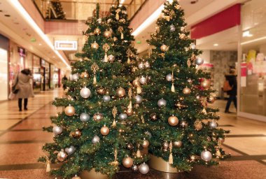 Noel ve Yeni Yıl kutlamaları için toplar ve çelenklerle süslenmiş iki yeşil kozalaklı ağaç. Bir alışveriş merkezinde.