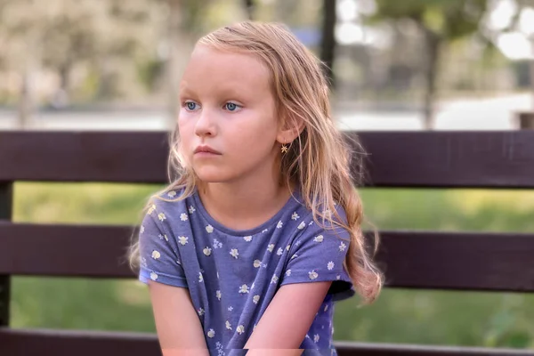 Mała Dziewczynka Blondynka Siedzi Niezadowolonym Spojrzeniem Zły Ławce Parku — Zdjęcie stockowe