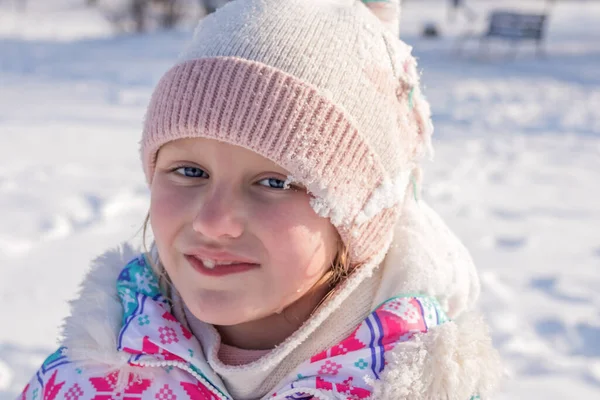 在雪的背景下 一个7 8岁女孩的冬季画像 她笑着张开嘴 没有乳牙 图库图片