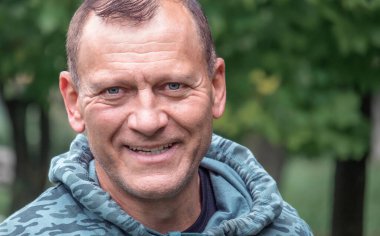 Orta yaşlı, yakışıklı Avrupalı bir adamın yakın plan çekimleri doğanın arka planına karşıdır.