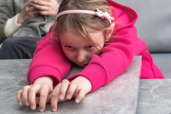 一个悲伤的女孩的画像 她7岁 靠在桌子上 胳膊前伸 — 图库照片