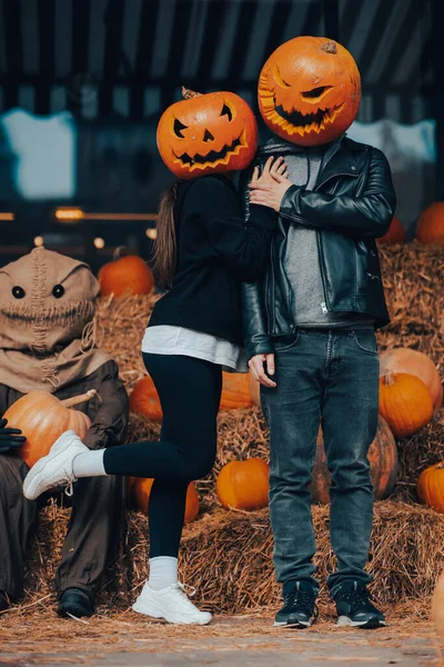 A guy and a girl with a pumpkin heads posing at the scarecrow — Stock Photo, Image