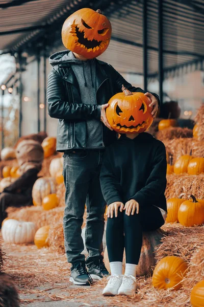 A guy and a girl with a pumpkin heads posing on the street — Stock Photo, Image