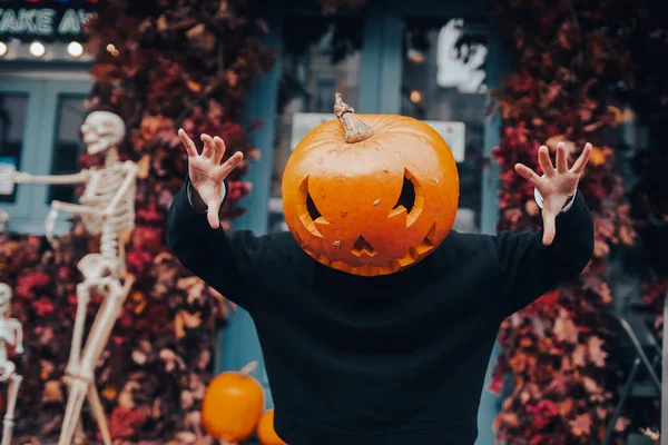Girl with a pumpkin head scares at the camera — Stock Photo, Image