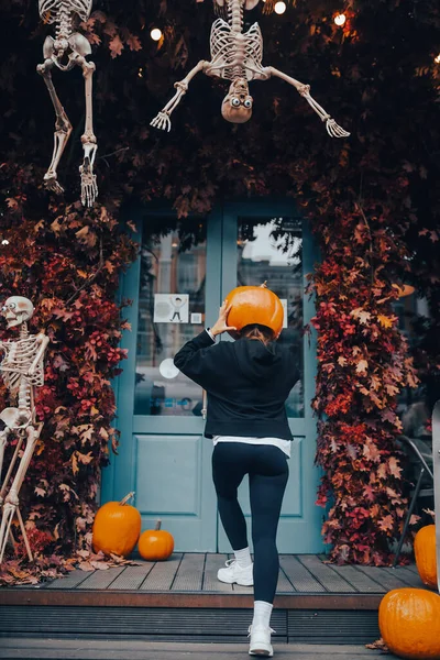 Girl with a pumpkin head posing at the door on the street — Stock Photo, Image