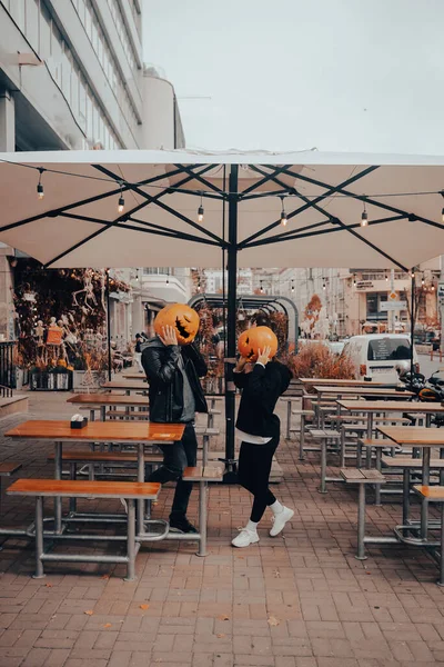 Kille och flicka med pumpa huvuden i en gata café — Stockfoto