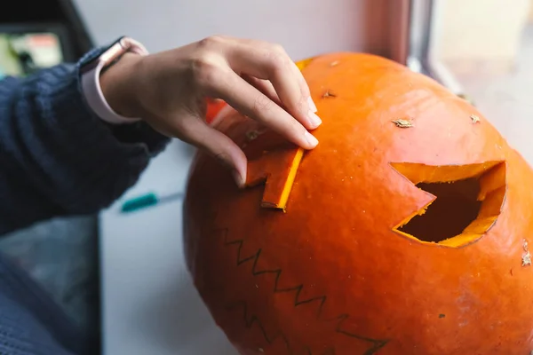 Hand of a young woman cutting out a Halloween pumpkin — Stock Photo, Image