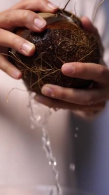 Kadın elleri hindistan cevizini açar, hindistan cevizi suyu dökülür.