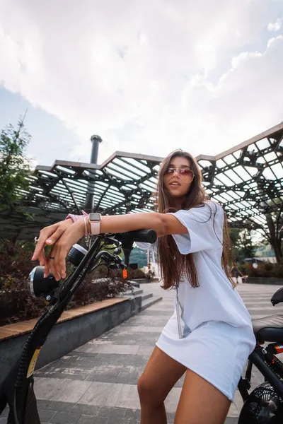 Young beautiful woman and an electric scooter, ecological transport — Stock Photo, Image