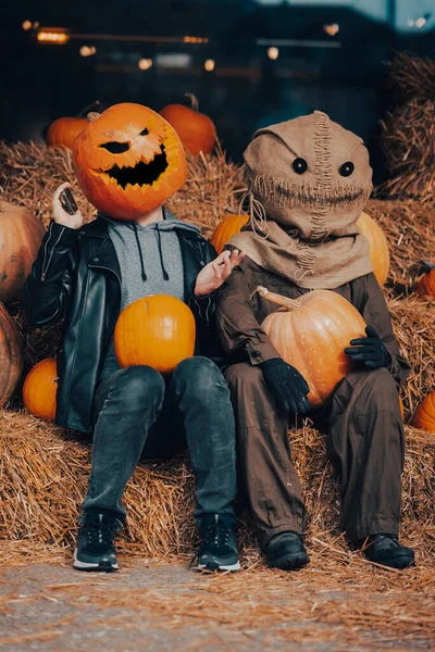 A guy with a pumpkin head sits next to a scarecrow — Stock Photo, Image