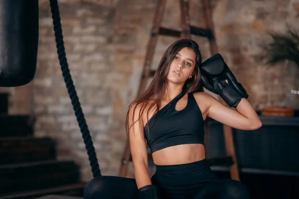 Menina fitness bonita posando na câmera em luva de boxe preto — Fotografia de Stock