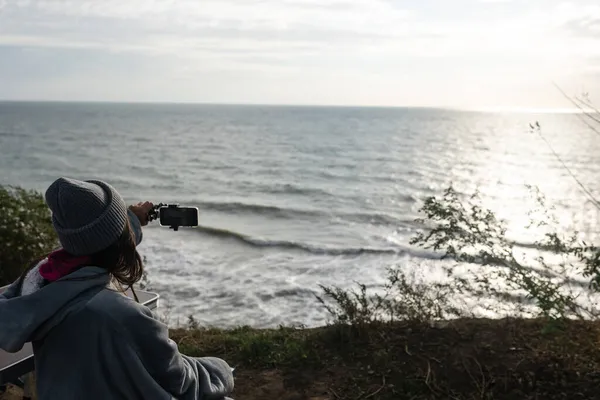 Młoda kobieta robi zdjęcie na smartfonie z pejzażem morskim — Zdjęcie stockowe