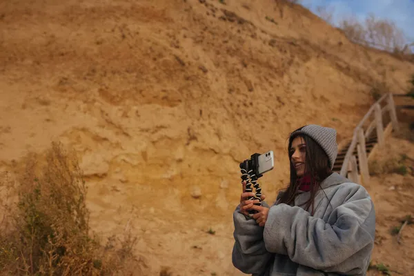 Mujer joven toma una foto en un teléfono inteligente del paisaje marino — Foto de Stock