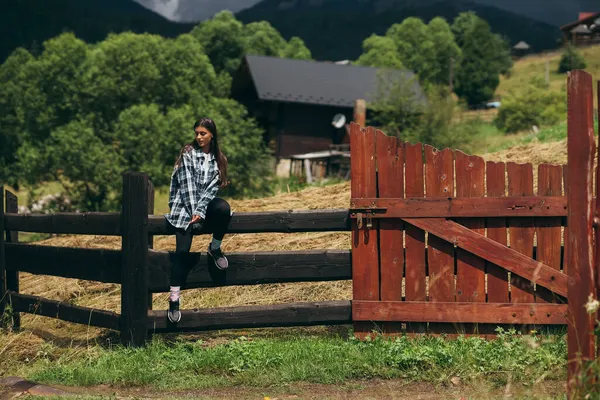 Молодая привлекательная белая женщина сидит на заборе — стоковое фото