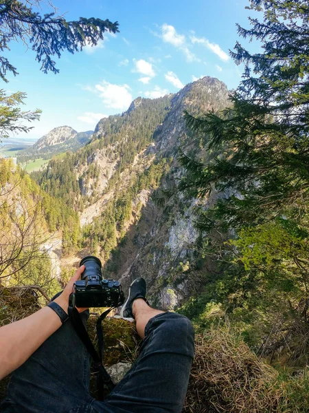 Ένας φωτογράφος παρατηρεί με την κάμερα στο χέρι από την κορυφή ενός βουνού. — Φωτογραφία Αρχείου